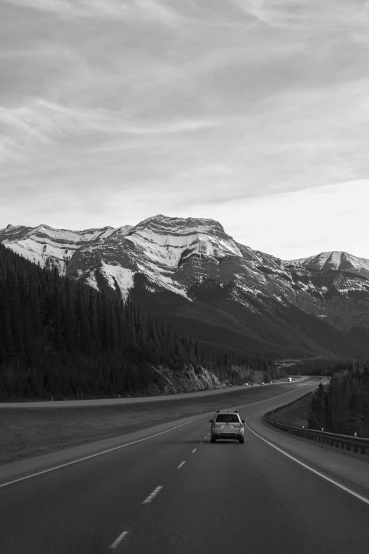 a car drives along the road surrounded by mountains