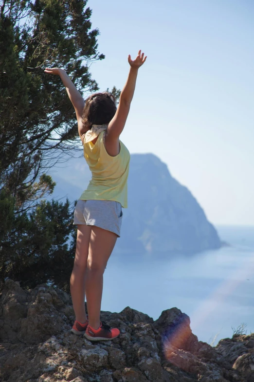 there is a woman standing on a rock reaching to the top of it