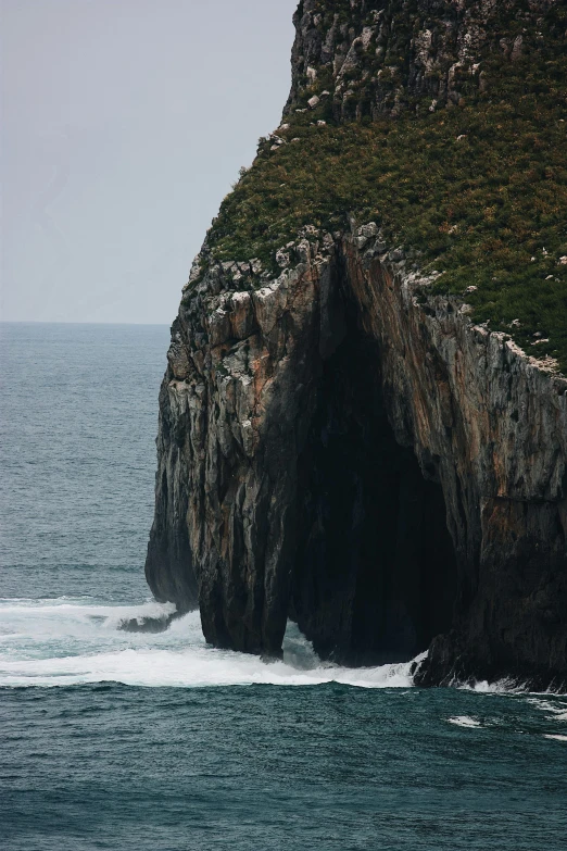 a man in an inflatable boat is coming out of a small cave