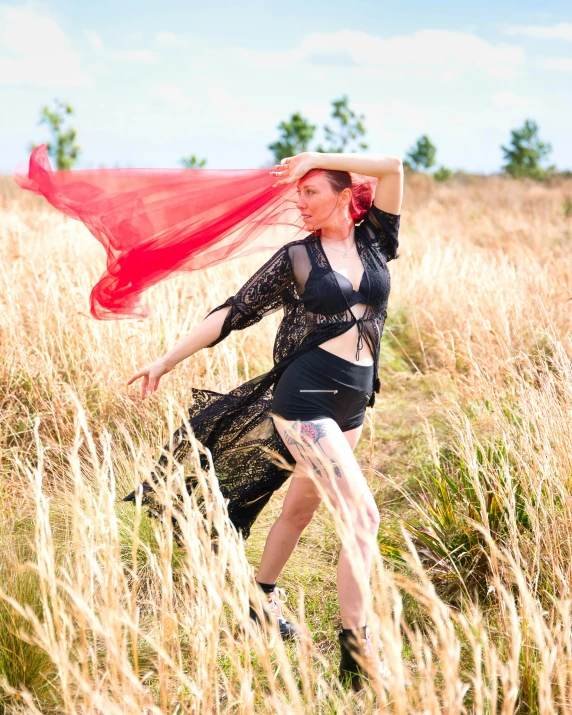 a woman is standing in a field holding her scarf