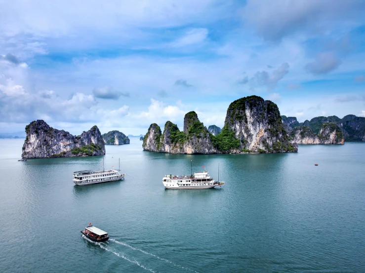 a number of boats in the ocean near rocks