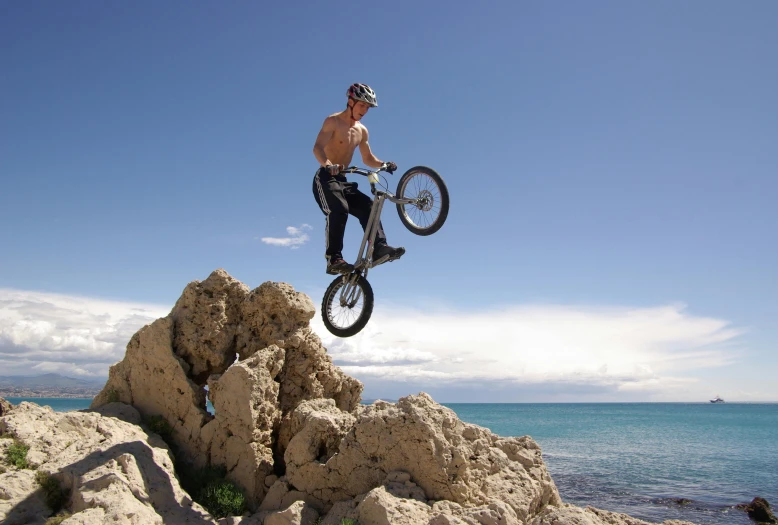 a shirtless man on a dirt bike does a trick