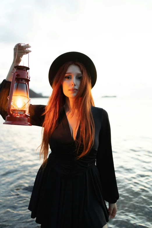 a woman with long hair wearing a hat and holding a lantern