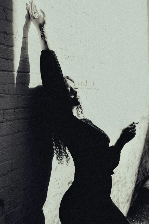 a woman leaning up against a brick wall