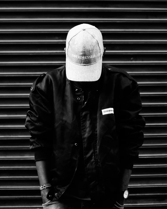 a person wearing a black shirt and hat and jeans and holding a skateboard