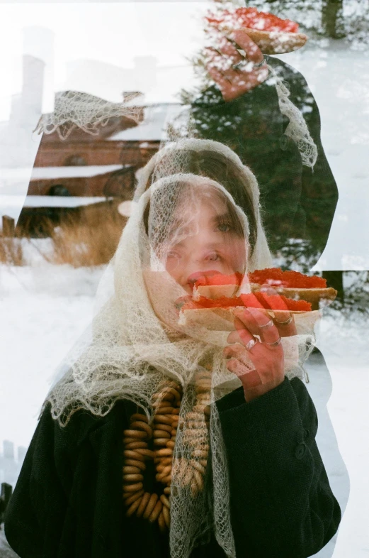 a person in a white lace veil and scarf holds carrots