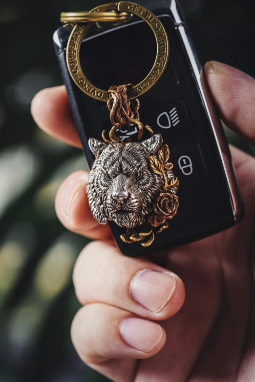 person holding a cell phone case with a floral key chain on it