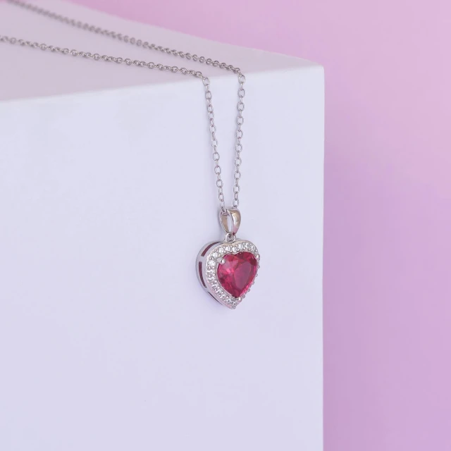 the tiny pink heart necklace has been placed on a box