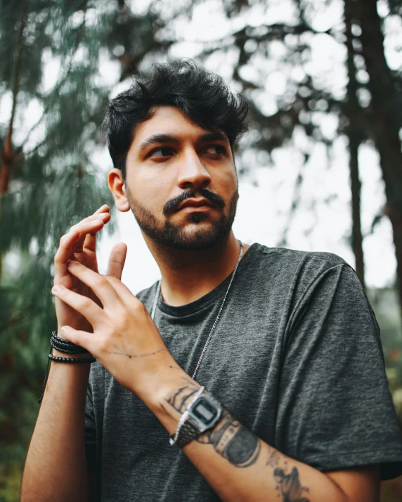 a man smoking in the woods holding a cigarette