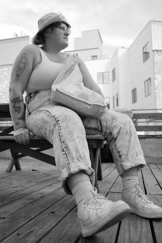 a lady sitting on a wooden bench with a bag