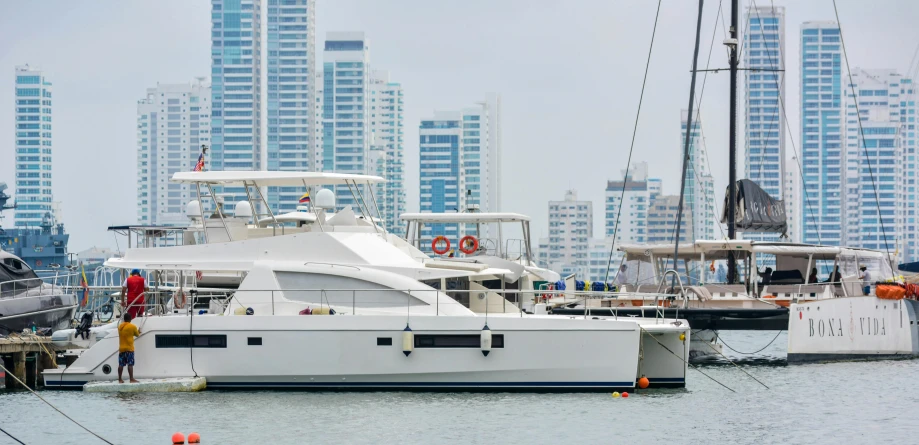 a yacht docked in a harbor with tall buildings in the background