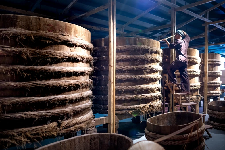 man climbing down on wood with large stacks behind him