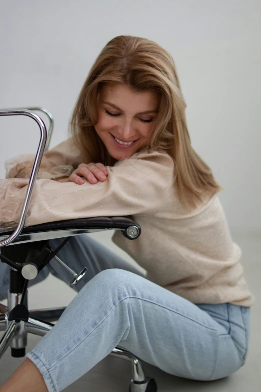 a woman is sitting in a chair, smiling
