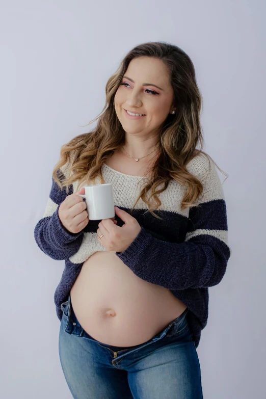 a pregnant woman is holding her coffee mug while smiling