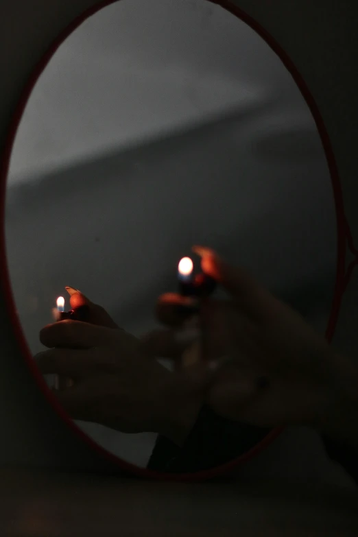 a woman holding out lit candles in front of her reflection