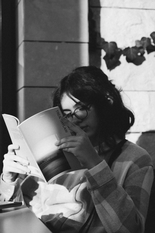 woman reading a book while sitting in a chair