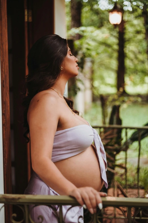 a pregnant woman leans against the balcony railing