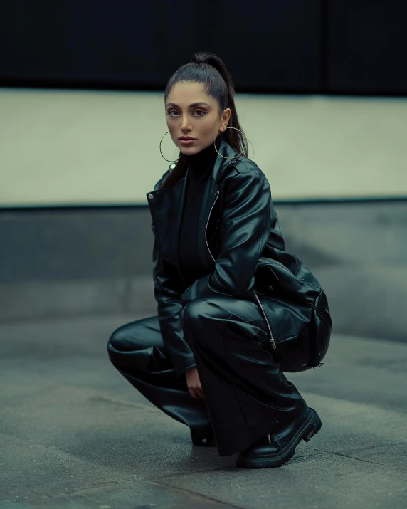 woman with pigtails squatting on the ground in black leather outfit