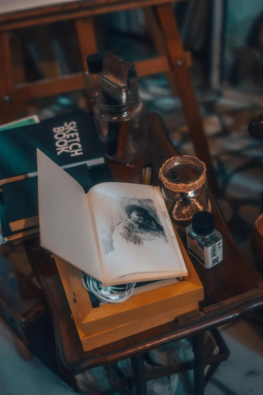 an open book sitting on top of a table next to ink bottles