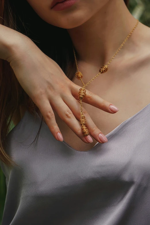 a woman wearing a gold chain is holding her hand out