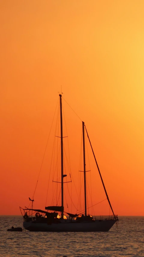 the sun is setting behind a boat sailing in the ocean