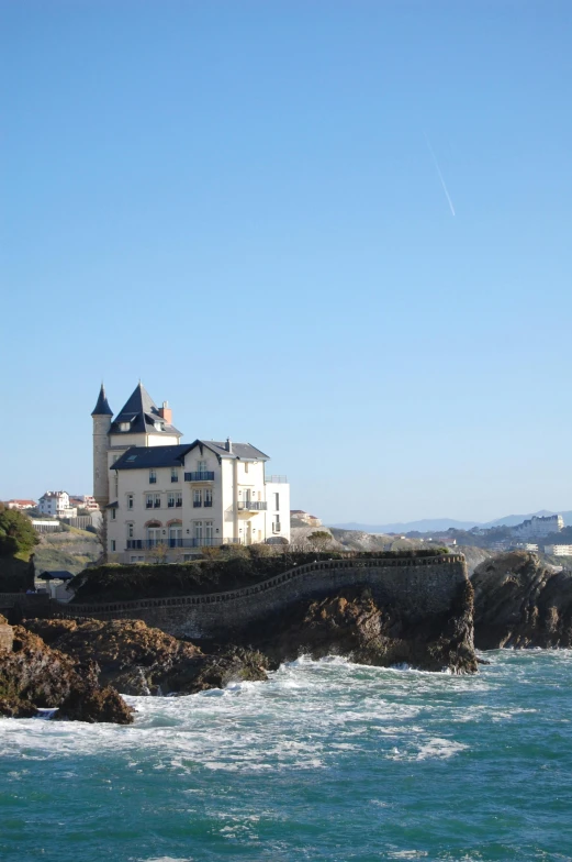 a lighthouse on a rocky shore with a large building in the background