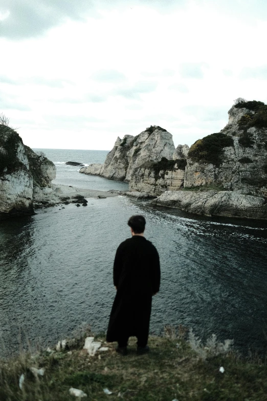 a man standing on a hill looking out at the water