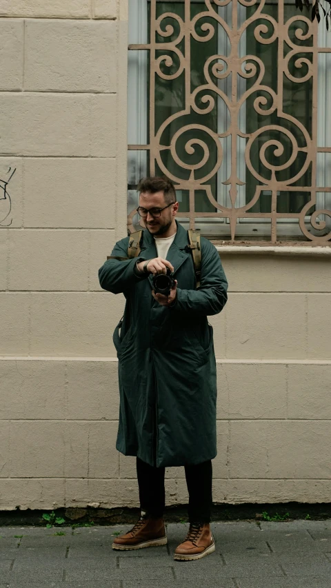 a man standing on a city street with his hands in the pockets of his pants