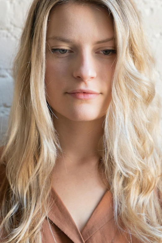 a blonde woman is posing in front of a wall