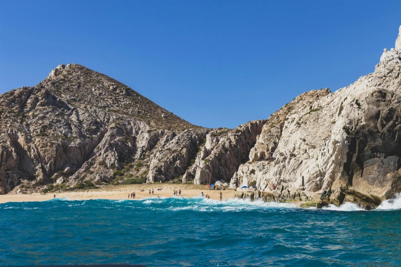 many people stand in the blue waters and cliffs