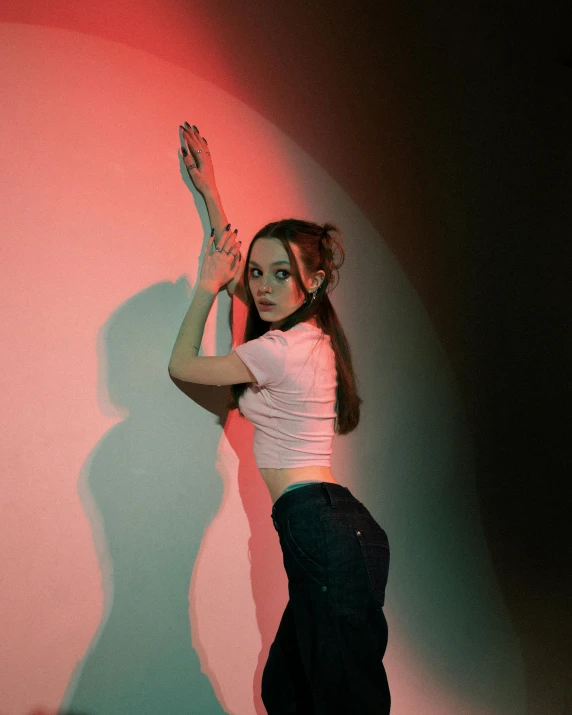 a woman is standing against a pink wall