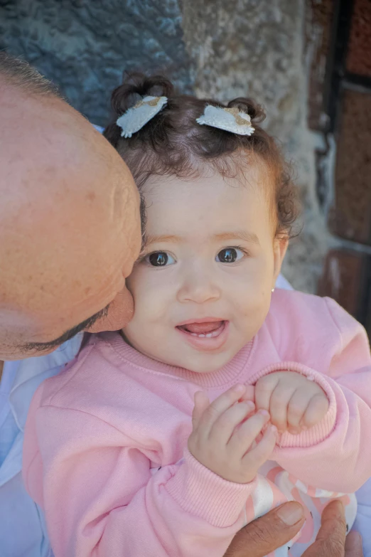 a baby smiles while a man kisses her