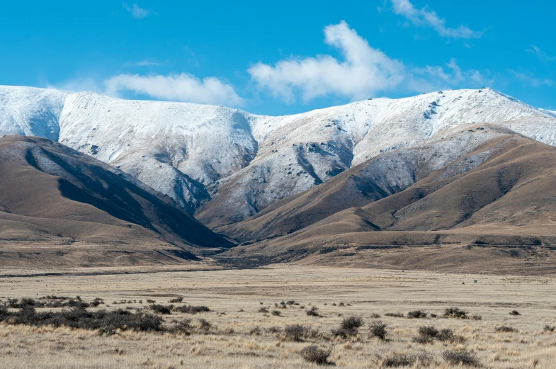 a large hill covered in snow with a field next to it