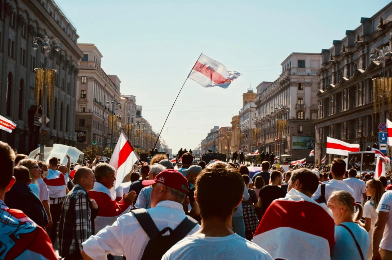 people wearing vests and holding flags walking on street