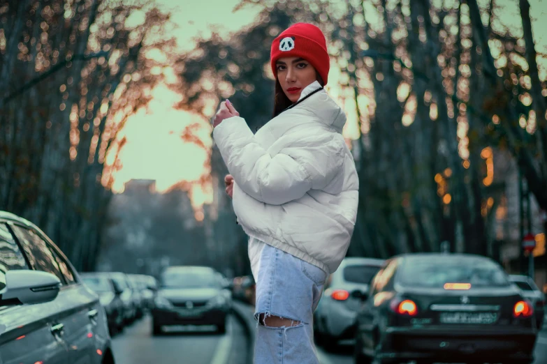 a woman with red hat and jacket stands on the sidewalk