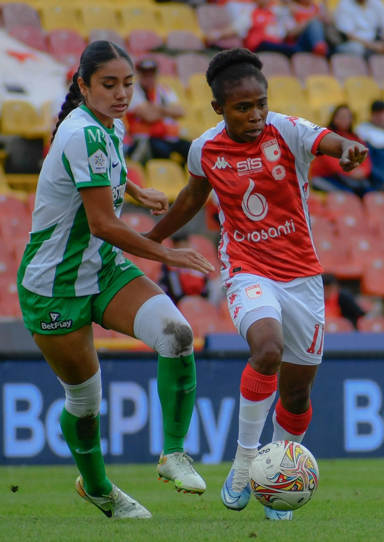 two women in uniform playing soccer on the field