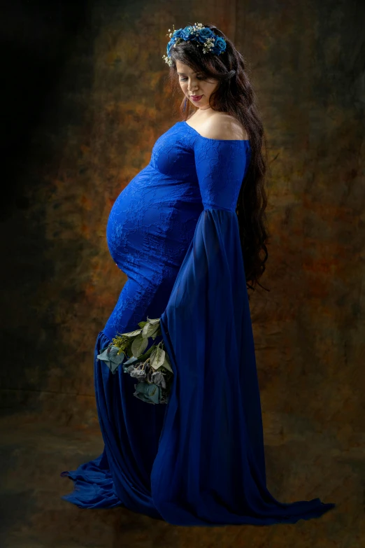 a pregnant woman wearing a blue dress with an intricately curled headpiece