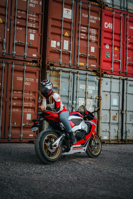 a red and white motorcycle next to many cargo containers