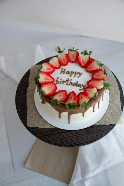 a strawberry cake on a table has a happy birthday greeting on it