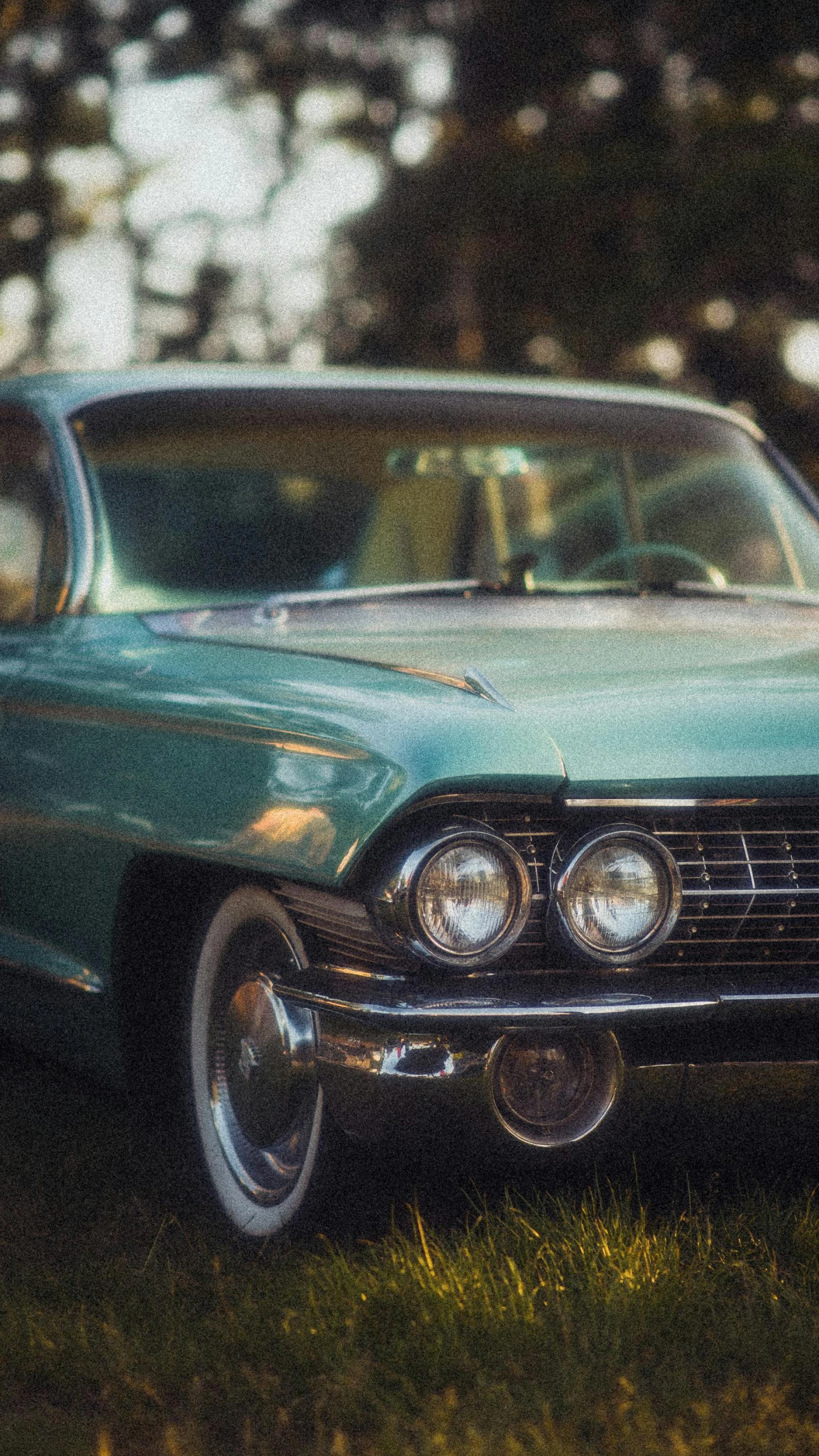 an old model car in the grass by the trees