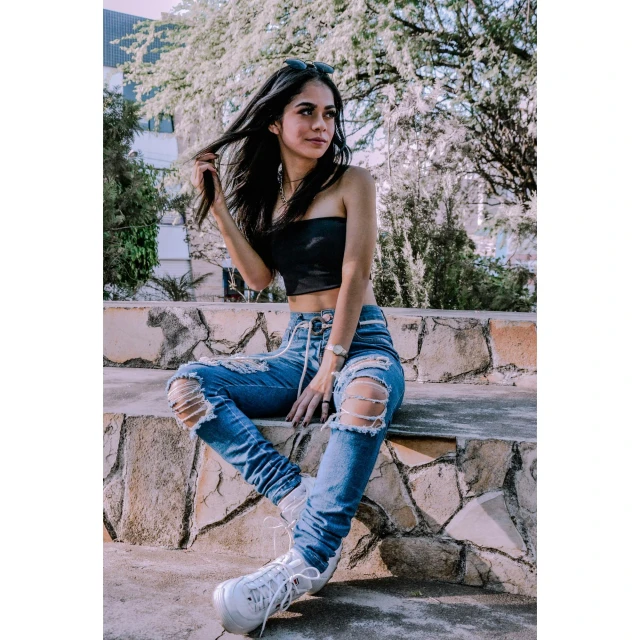 the woman in the destroyed jeans is sitting on a bench