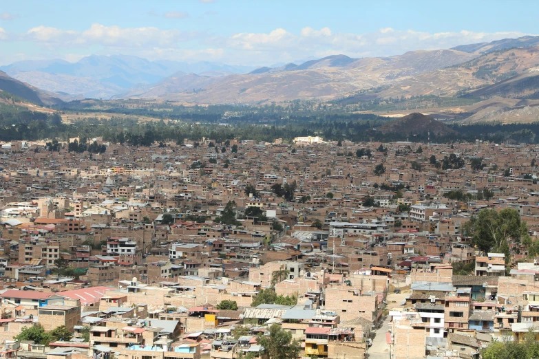 many small buildings in the foreground of a town and mountains in the background