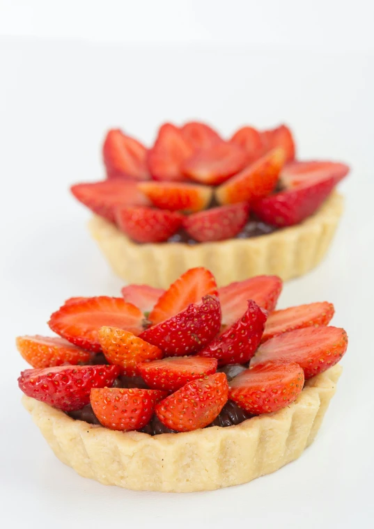 three tarts with strawberries and jam spread on top