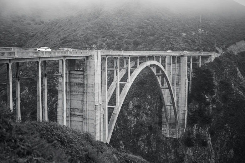 a bridge and truck crossing over it in the mountains