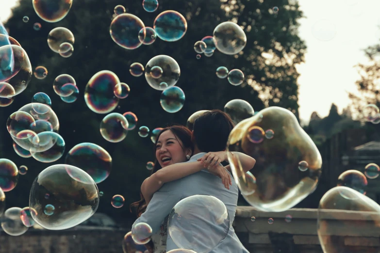 a man and woman hug with soap bubbles floating around them