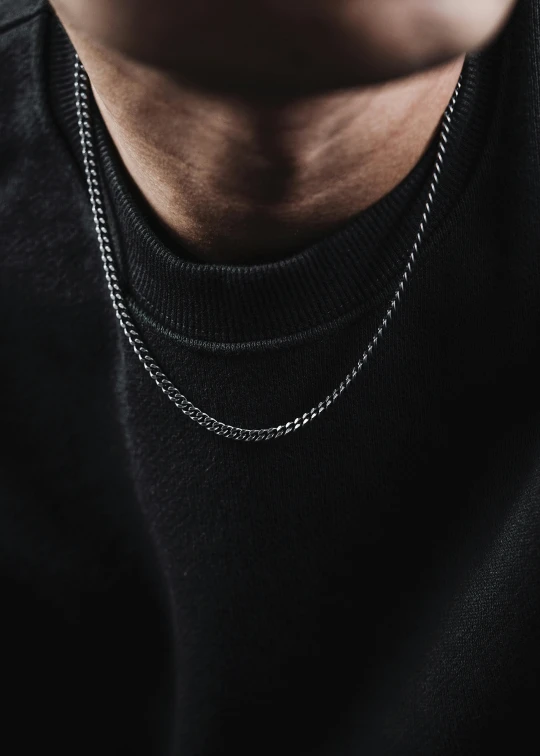 a man wearing a necklace with a chain hanging from his chest
