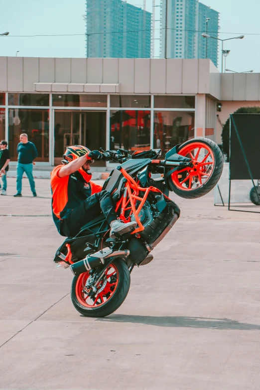 motorcycle with orange and black accents in front of buildings