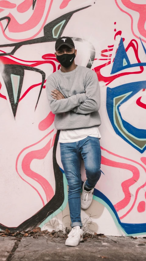 a young man standing near a wall with graffiti on it