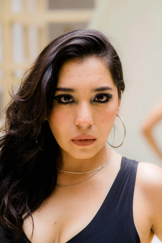 an asian woman with dark hair and large hoop earrings posing