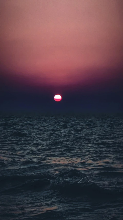 a sun over the ocean, rising above a small boat